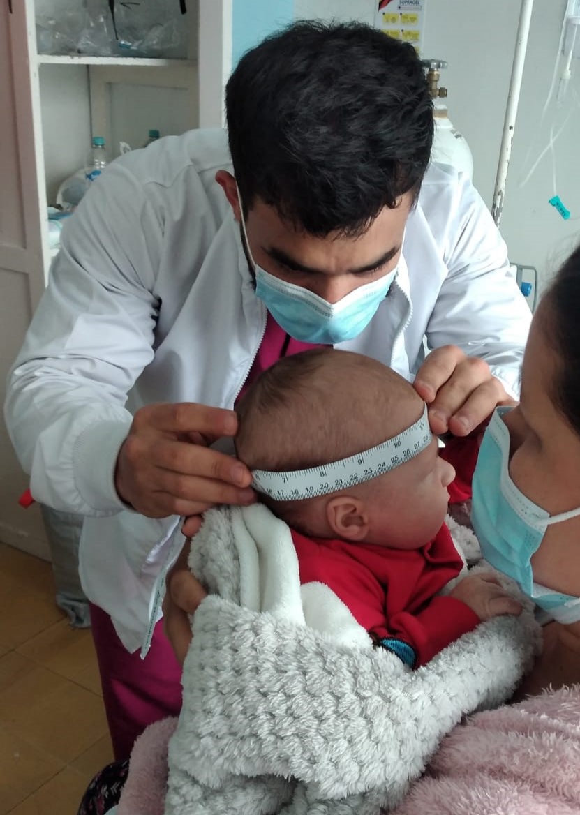 Pedro Barrera midiendo el perímetro cefálico de un lactante durante una valoración nutricional